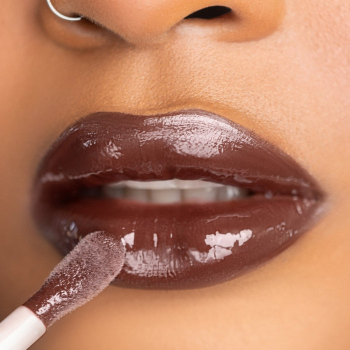 Lip-on model shot: Brownie Bae Nude Glass Gloss applied on medium to deep skin tone — pigmented high-shine finish